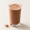 Cocoa protein shake in a clear glass on a cream background.